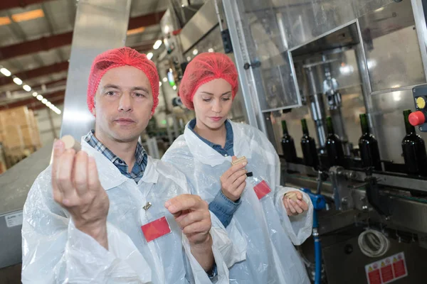 Dos trabajadores analizando un tapón de corcho de una botella — Foto de Stock