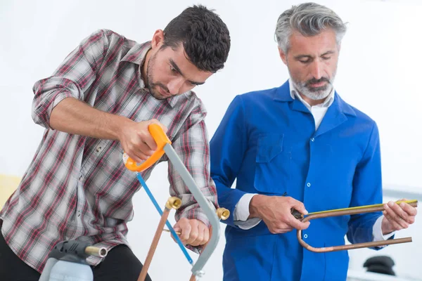 Carpinteiro mostrando aprendiz como usar máquina de serrar — Fotografia de Stock