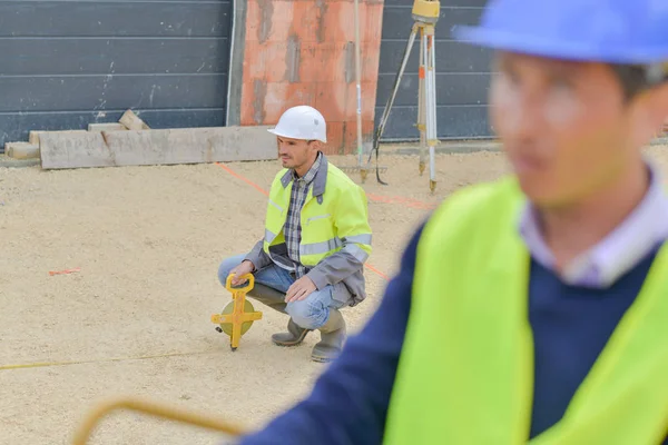 Constructores que utilizan herramientas de medición al aire libre en una obra de construcción —  Fotos de Stock