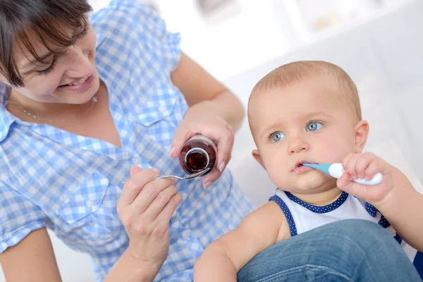 De vrouw geeft aan de zieke baby geneeskunde — Stockfoto