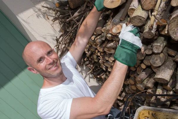 Sorrindo homem arrumando troncos de madeira — Fotografia de Stock