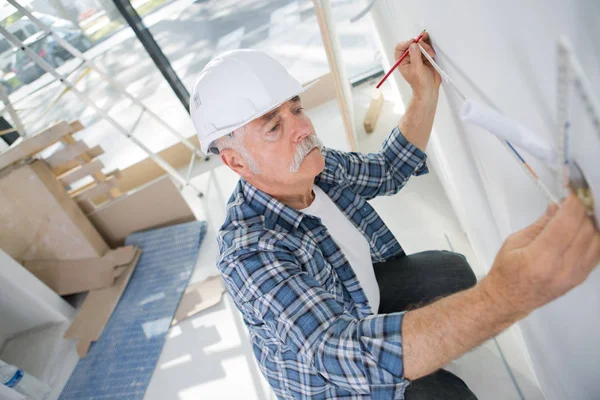 Viejo trabajador de la construcción midiendo la pared — Foto de Stock