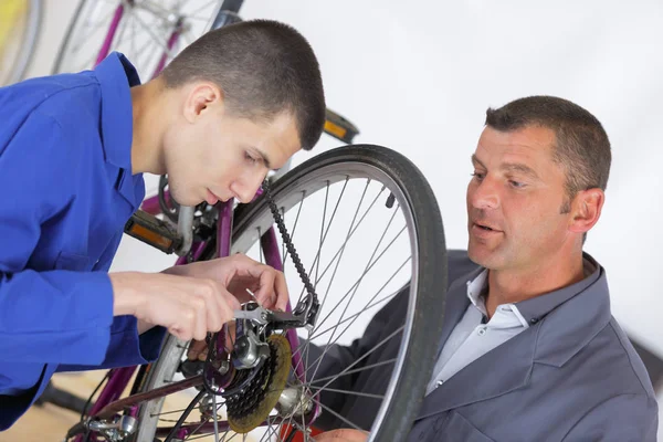 Leraar aprentice toont hoe te repareren van een fiets — Stockfoto