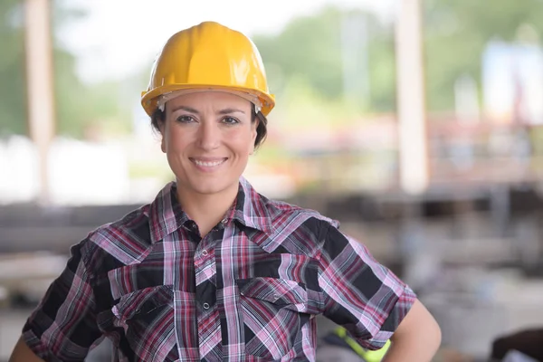 Trabalhador feminino sorridente usando um capacete amarelo — Fotografia de Stock