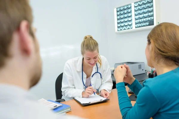 Sorridente jovem médica dando resultados aos pacientes — Fotografia de Stock