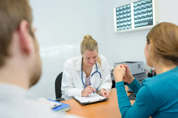 Schlanke junge Ärztin gibt Patienten Ergebnisse — Stockfoto