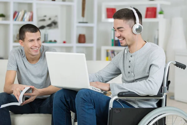 Jovem deficiente e amigo verificando música em um laptop — Fotografia de Stock