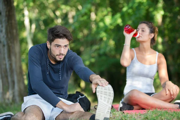 Couple s'étirant à l'extérieur tout en buvant de l'eau — Photo