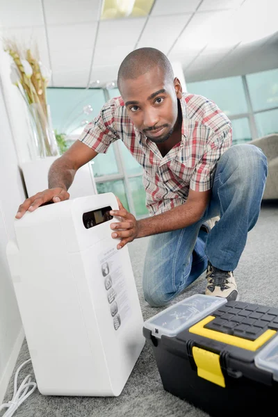Crouching by an air conditioning unit — Stock Photo, Image