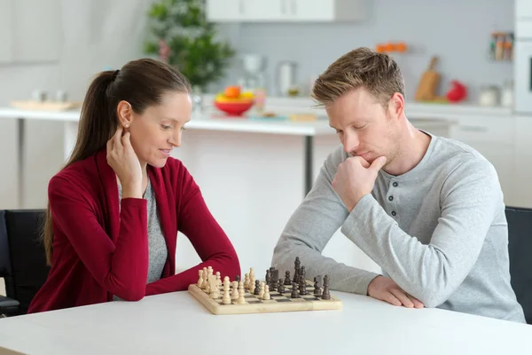 Heureux jeune couple jouant aux échecs dans le salon — Photo