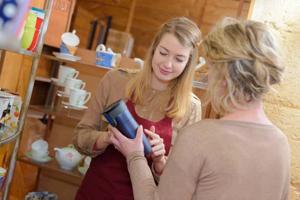 Young woman serving customer in shop — Stock Photo, Image