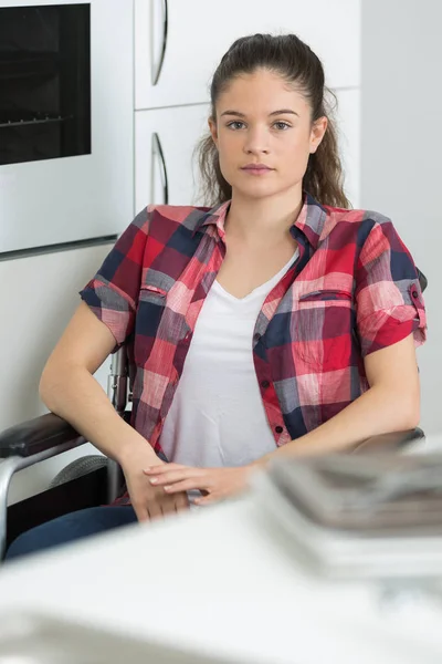 Jovem mulher em cadeira de rodas na cozinha — Fotografia de Stock