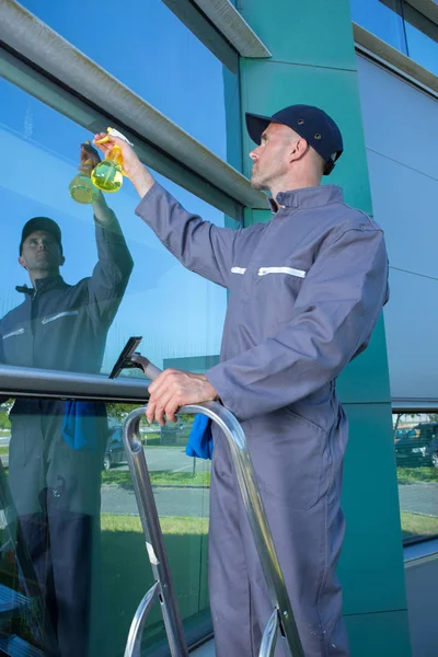 Happy mature male worker cleaning glass — Stock Photo, Image