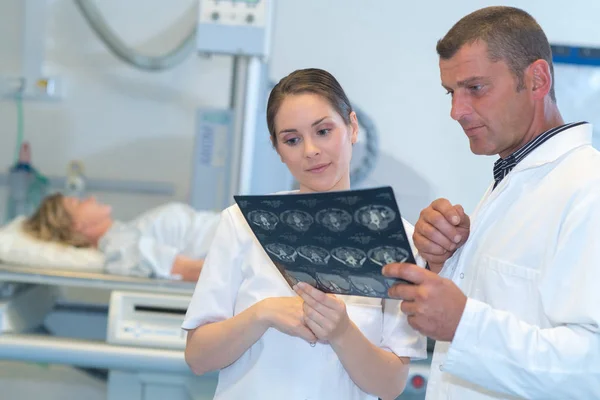 Doctor analyzing and talking with assistant about x ray results — Stock Photo, Image