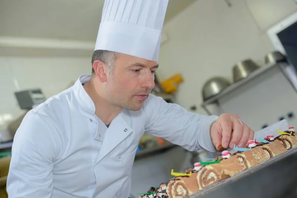 Pastry chef finishing off christmas logs — Stock Photo, Image