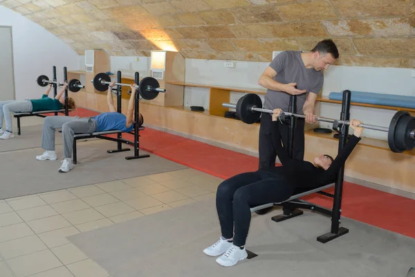 Personlig manliga tränare hjälpa ung kvinna med lyfta skivstång — Stockfoto
