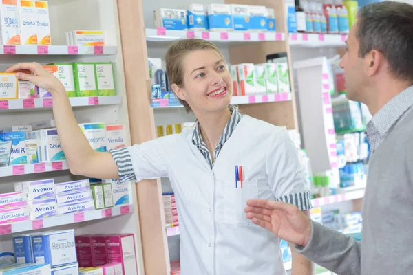 Farmacêutico profissional ajudando um cliente — Fotografia de Stock