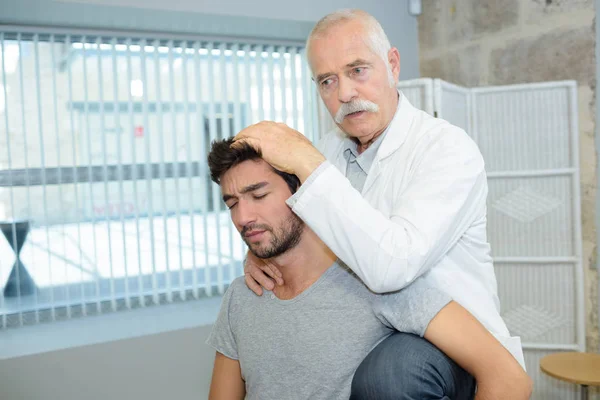 Viejo médico revisando a un paciente con problemas en la cabeza —  Fotos de Stock