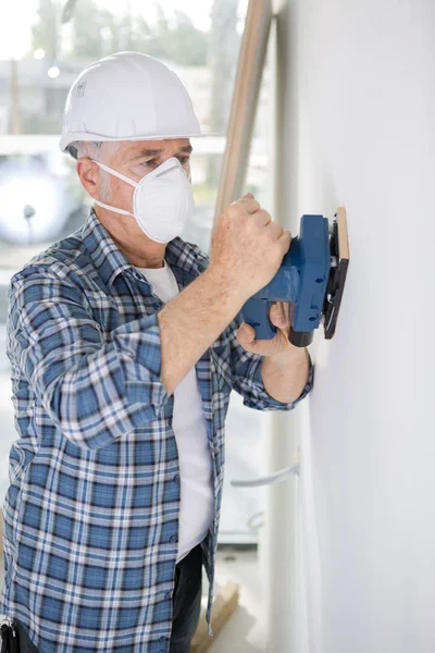 Olde man repainting a wall indoors — Stock Photo, Image