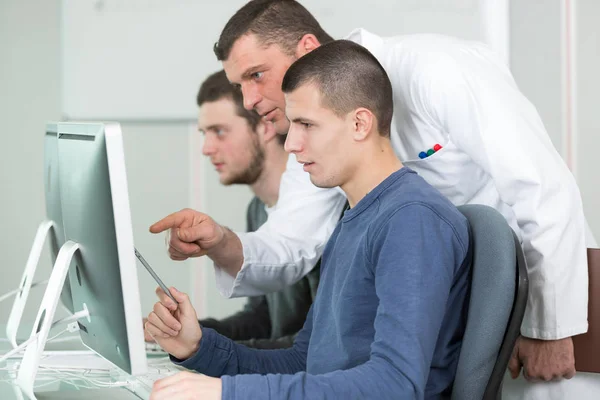 Tutor e jovens estudantes em aula de computação — Fotografia de Stock