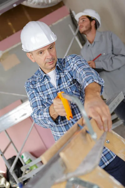 Snickare skär tak stöder på byggnadsplatsen — Stockfoto