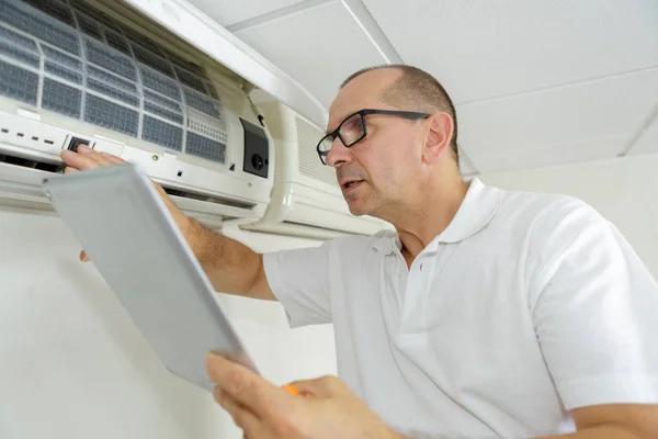 Homem verificando manual de ar condicionado ao usá-lo — Fotografia de Stock