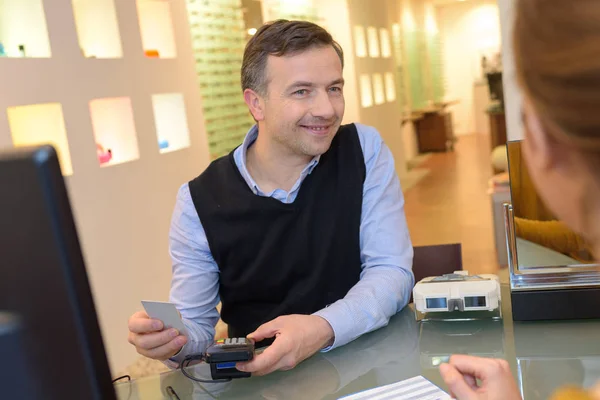Optician issuing credit card to a customer — Stock Photo, Image