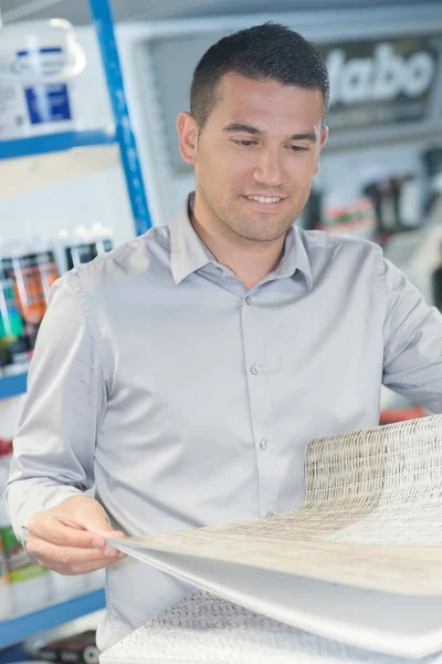Man buying wallpaper at hardware store for do-it-yourself project — Stock Photo, Image