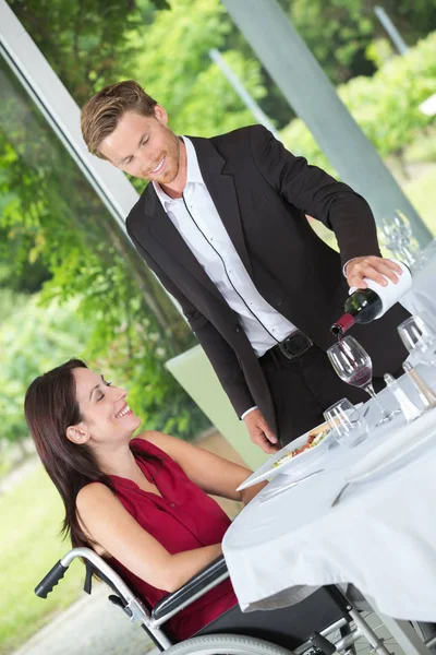 Mann schenkt seiner behinderten Frau ein Glas Wein ein — Stockfoto