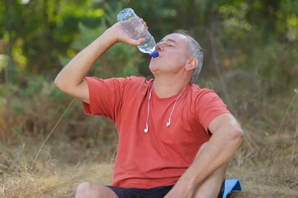 Homem bebendo garrafa de água em um parque — Fotografia de Stock