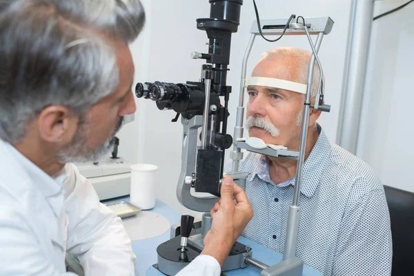 Oftalmólogo haciendo una prueba ocular en un paciente viejo — Foto de Stock