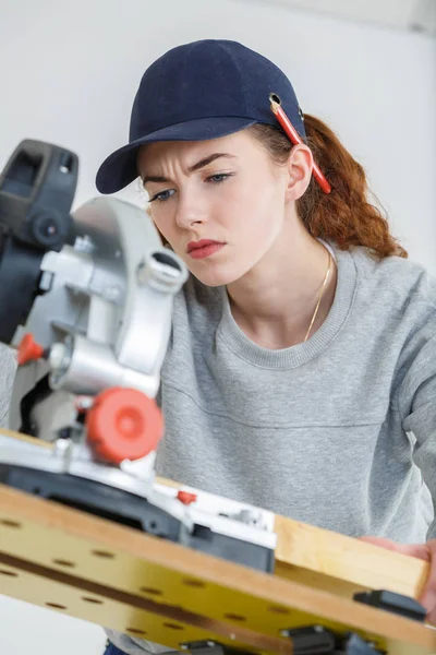 Junge Tischlerin schneidet in Werkstatt mit Tischsäge Holz — Stockfoto