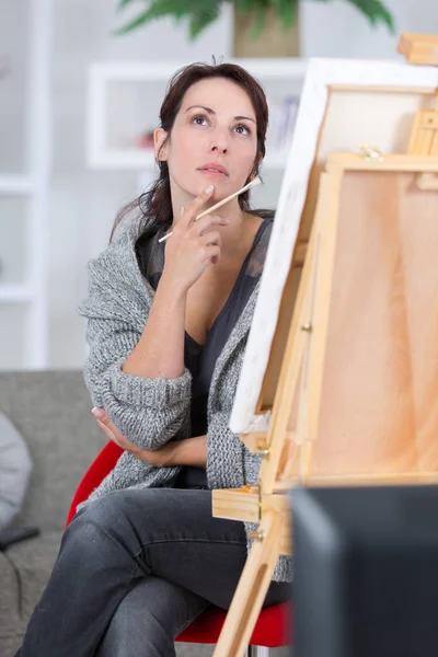 Tankeväckande ganska ung kvinna artist tänkande nära hennes måleri — Stockfoto