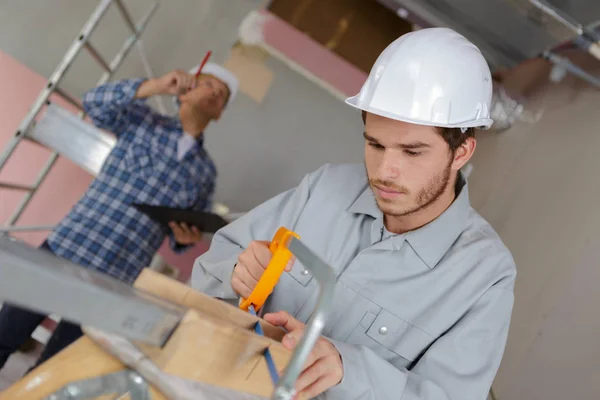 Ung man skära en styrelse med en hand såg — Stockfoto