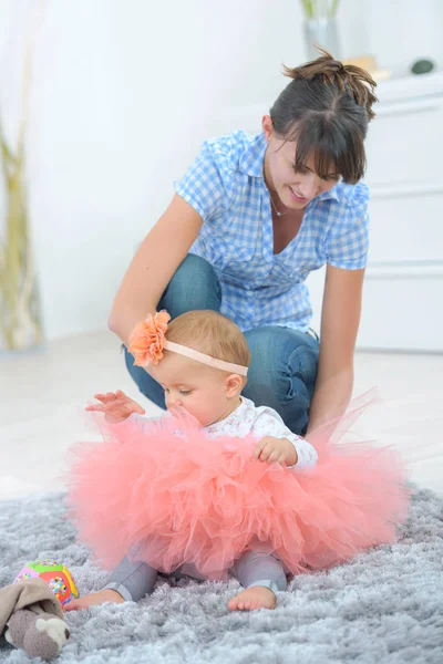 Mother dressing her daughter in the morning in bedroom — Stock Photo, Image