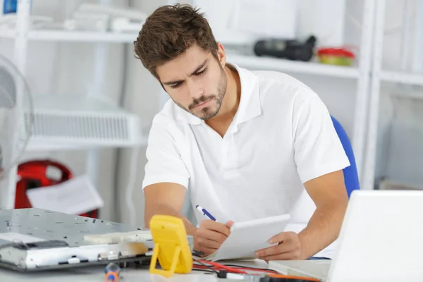 Young engineer taking notes while developping new induction hobs — Stock Photo, Image