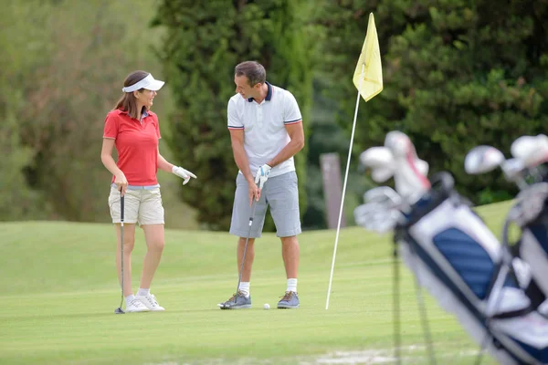 Hombre enseñando a una mujer a jugar al golf — Foto de Stock