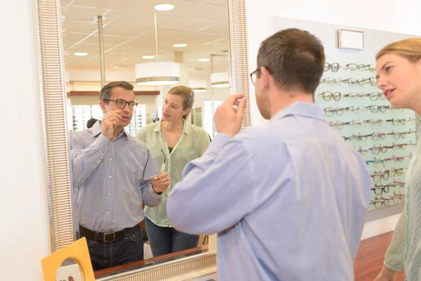 Atractivo optometrista y hombre eligiendo un nuevo marco —  Fotos de Stock