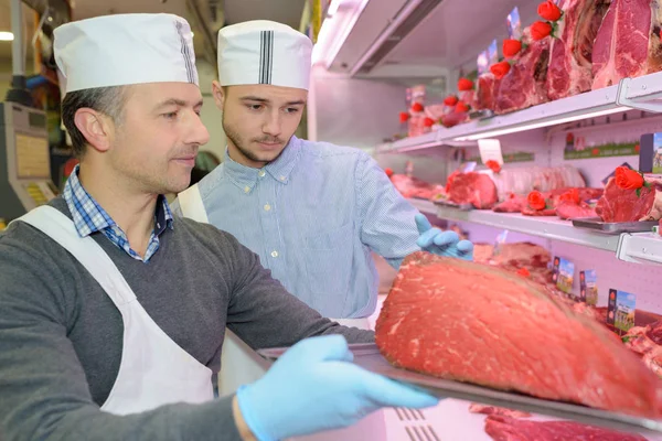 Butcher restocking shelf and butcher — Stock Photo, Image