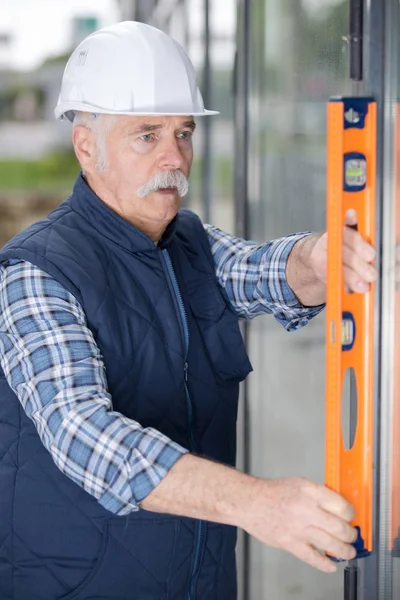 Senior metselaar met behulp van een waterpas — Stockfoto