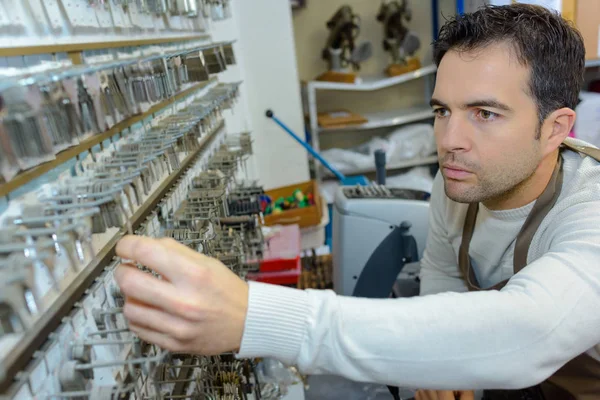 Cobbler selecting key from wall display — Stock Photo, Image