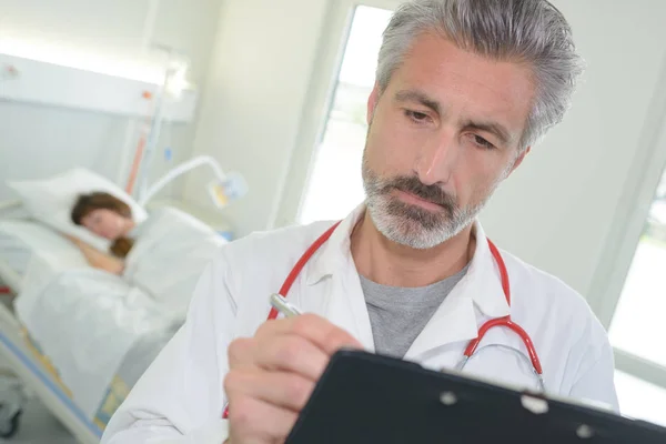 Portrait of handsome doctor writing on clipboard — Stock Photo, Image