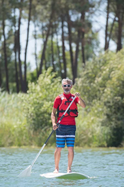 Uomo godendo di un giro sul lago con paddleboard — Foto Stock