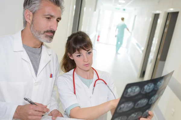 Trabajadores médicos masculinos y femeninos mirando rayos X — Foto de Stock