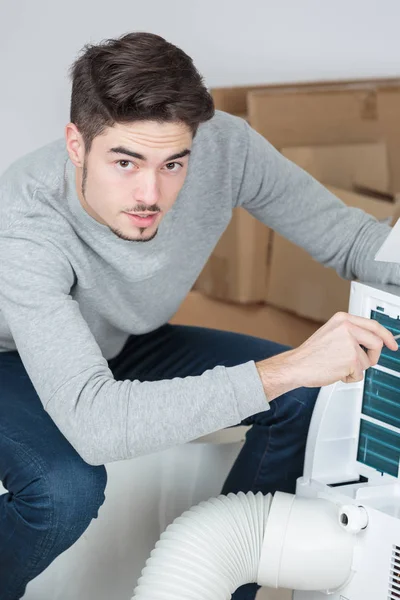 Przystojny młody mężczyzna elektryk instalacji klimatyzacji w domu klienta — Zdjęcie stockowe