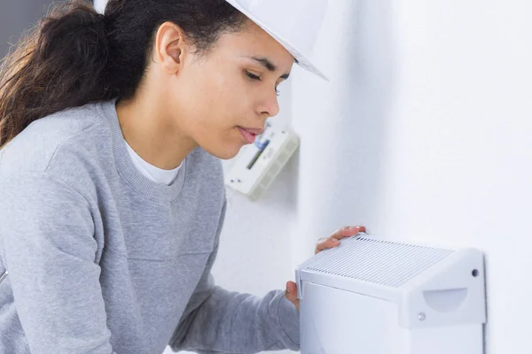 Arbeiterin montiert Gerät an Wand — Stockfoto