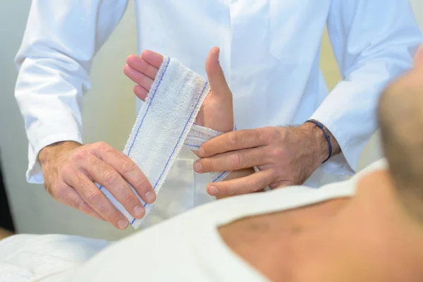 Doctor bandaging his patient hand in medical office — Stock Photo, Image