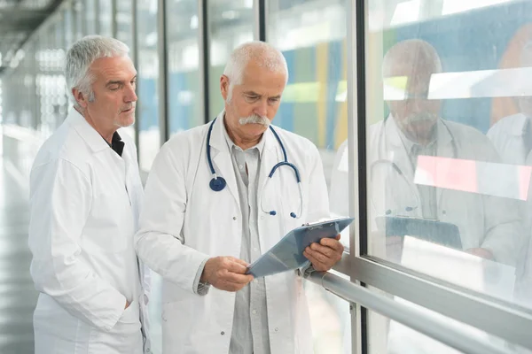 用剪贴板在医院走廊的两个男医生 — 图库照片