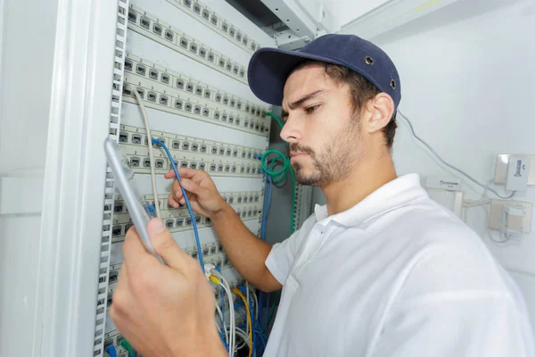 Eletricista focado aplicando procedimento de segurança enquanto trabalhava no painel elétrico — Fotografia de Stock