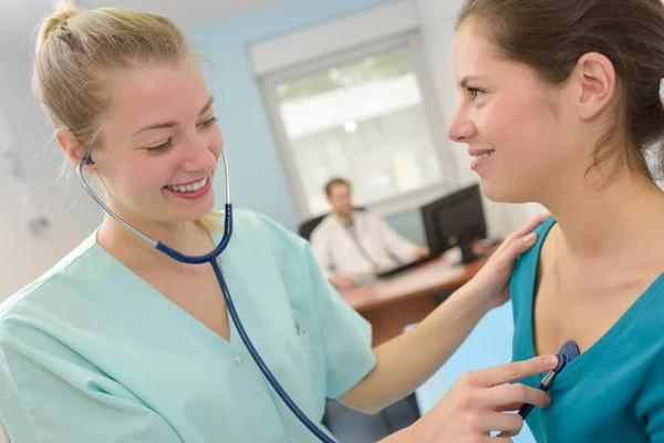 Junge Ärztin mit Stethoskop und Patientin in einer Praxis — Stockfoto